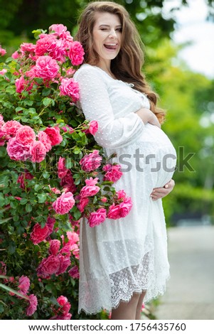 Pregnant woman in nature. Beautiful woman holds belly.