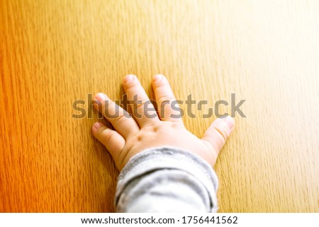 Child's hand showing the five fingers isolated on a wooden background and copy space.