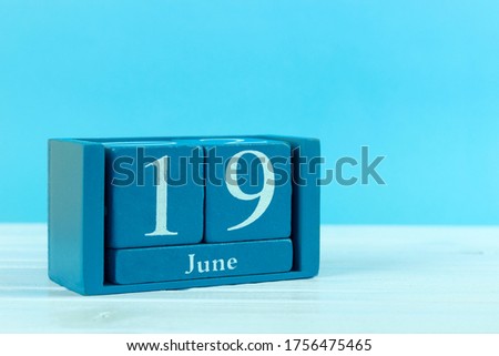 wooden calendar with the date of June 19 on a blue wooden background, World Sickle Cell Anemia Awareness Day, World Walking Day, World Children's Football Day