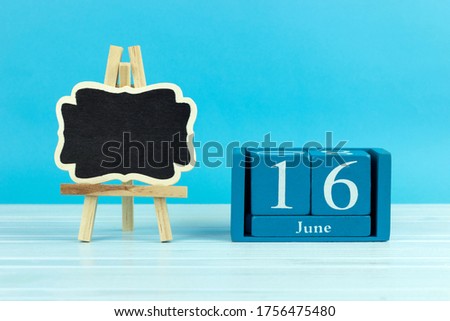 wooden calendar with the date of June 16 and an easel on a blue background, place for text, World seaTurtle Day