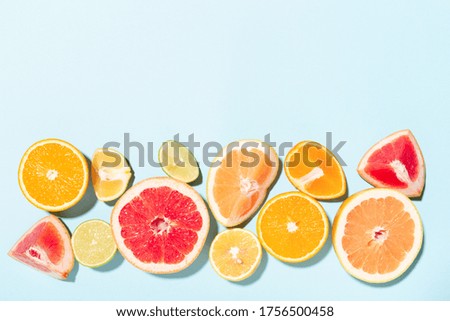 Border made of mix of citrus fruits on blue background. Top view with copy space.