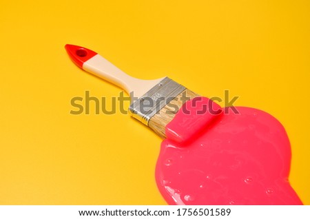 Shot of a brush with pink sticky slime on yellow background. Minimalism in photography, concept creative picture. Painting tool
