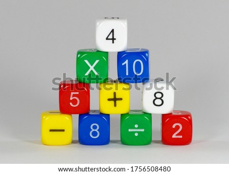 Pyramid stack of coloured dice showing numbers and mathematical symbols