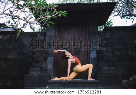 Strong 20s caucasian female in active wear enjoying training and recreation during yoga practise, tranquil woman stretching muscles and feeling body vitality and spiritual harmony near temple