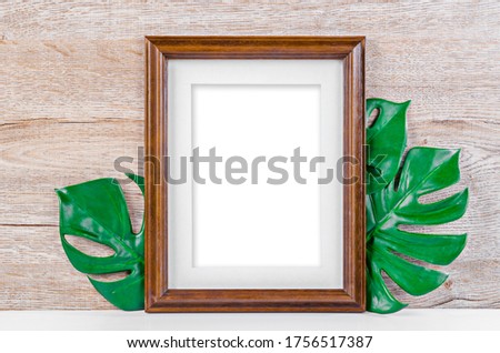 Empty wooden photo frame on green leaves on wooden background, Save Clipping path.
