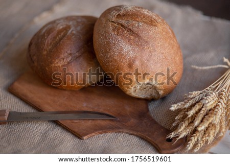 Two fresh baked breads and a knife are on the table. Brown coarse grain bread. 