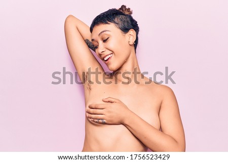 Young beautiful woman shirtless smiling happy. Standing with smile on face showing hairy armpit over isolated pink background