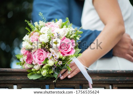 A close-up image of the hands of the bride and groom, holding each other and a bouquet of a beautiful white and pink flower pink. Close-up image of details of wedding decorations.