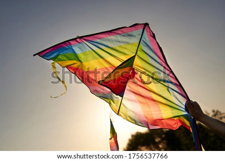 Bright multi-colored kite in a woman's hand against the sky, the theme of summer fun.