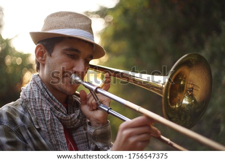 Musician playing the trombone outdoors in a park. Royalty-Free Stock Photo #1756547375