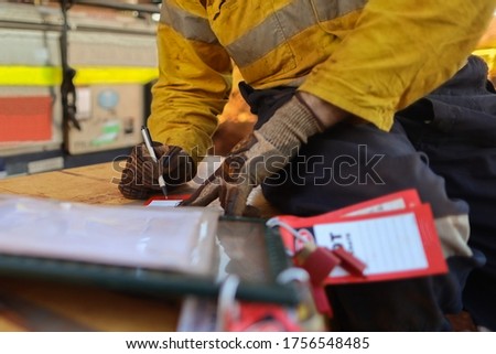 Safety workplace defocused construction worker holding white pen writing his name on personnel isolation red danger tag it attached with personal lock together with safety isolation permit lock box   Royalty-Free Stock Photo #1756548485