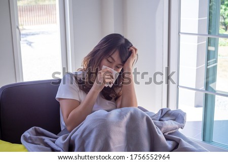 An Asian woman sick on the sofa in the house. Women have headaches, high fever and runny nose due to flu. The concept of illness with influenza Royalty-Free Stock Photo #1756552964