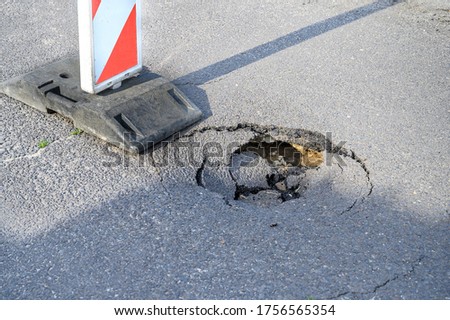 Pothole on asphalt street with detour alert traffic sign  