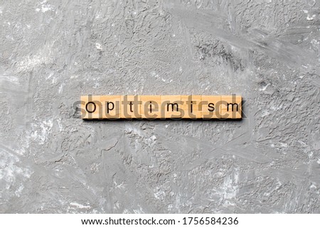 Optimism word written on wood block. Optimism text on cement table for your desing, concept.