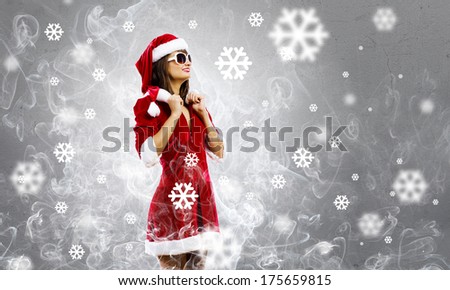 Attractive young girl in Santa suit against color background