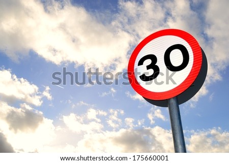Thirty mile per hour street sign with dramatic clouds in background.