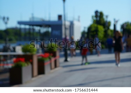Blurred background. A group of people walking on the embankment of the city. City life. Silhouettes of people.