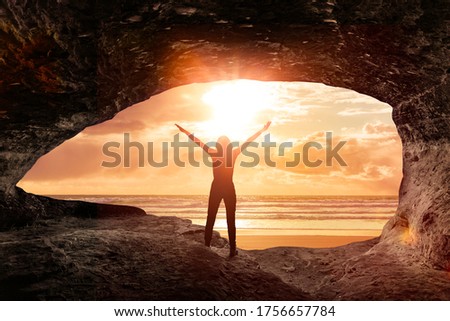 Silhouette of a woman welcomes the sunrise in a cave Royalty-Free Stock Photo #1756657784