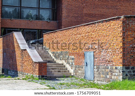 Brick-lit walls with a door to the utility room and a staircase leading to the main entrance to the building