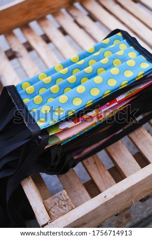 Several layers of the colorful squares of fabric, which were cut out, are being sewn together with thread and folded accordingly before the ribbon is attached. Presented in colorful stacks.