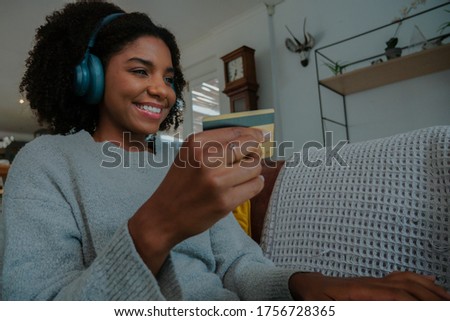 Happy woman making an online purchase with credit card on the sofa at home