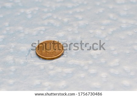 a coin of ten rubles is on the ice surface. freezing ruble