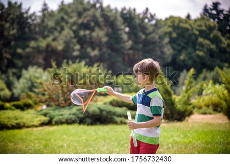 Little boy playing with his soap bubbles toy in the park. Child activity. Springtime concept.