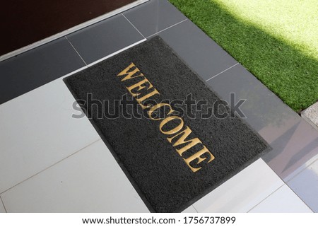 Black Welcome carpet on floor.