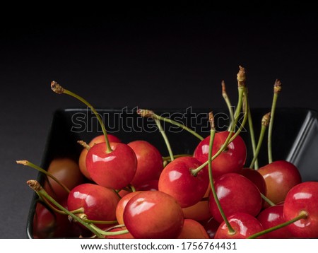 Ripe cherries on a black background. Pink berry.