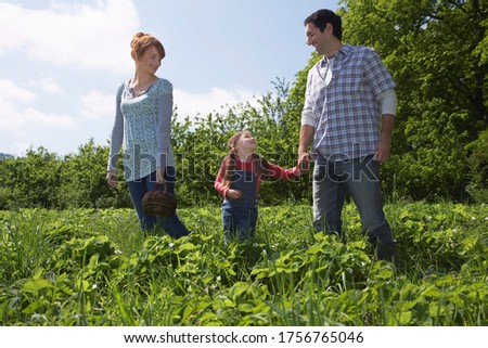 Parents and daughter (5-6) in countryside