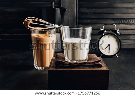 Whipped instant coffee. New popular food and drink trend. One glass of Korean Dalgona coffee with oat milk on dark background. Selective focus