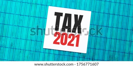 blank note pad with TAX 2021 text on green wooden background