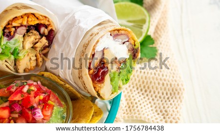 Mexican traditional authentic homemade Burrito with pulled pork beef chili con carne serve with tomato salad and avocado guacamole and dip sauce