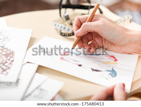 Dressmaker is drawing a fashion sketch. Close up of the hands