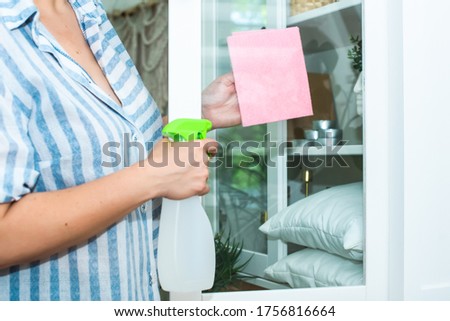 adult, old woman washes a glass cabinet door. in the hands of a pink rag and cleanser secol. bright horizontal photo