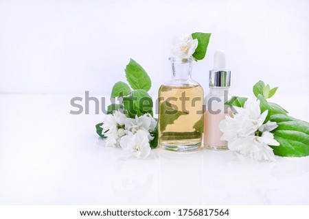 Essential oil and cream with jasmine flower. Aromatherapy and alternative medicine. Jasmine tincture in a glass jar and a lot of fresh buds. Soft focus, photo light colors. Copy space
