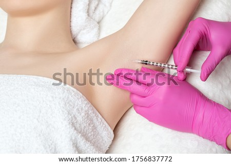 The doctor makes injections of botulinum toxin in the underarm area against hyperhidrosis. Women's cosmetology concept. Royalty-Free Stock Photo #1756837772