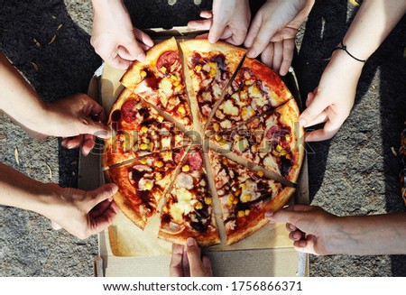 People hands taking slices of pizza on stone background. Nature. Picnic. Camping trip.