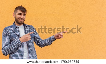 the Happy man makes a hand gesture against the backdrop of an orange wall