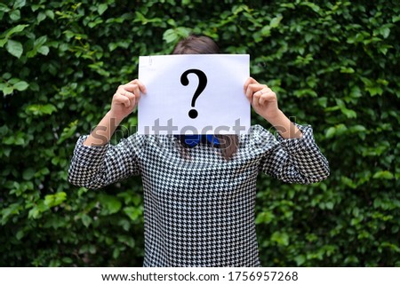 Asian Woman Holding Paper With Question Mark, The background is a leaf wall.