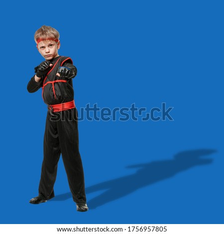 Teen athletic boy in black kimono training attack movements