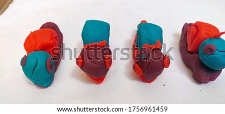 red, purple and blue plasticine formed into snails