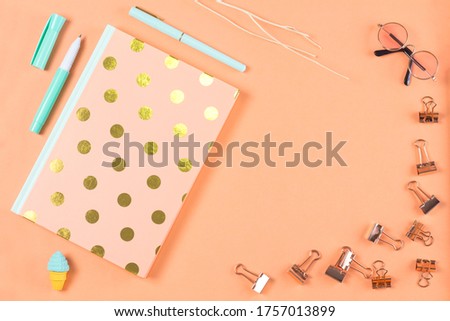 flat lay stationery on work desk in orange pastel background	

