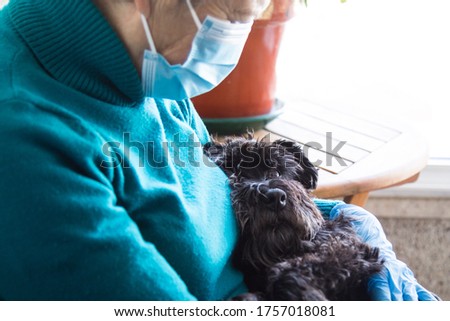 senior woman with disposable medical mask and her dog. Safety in public places during the coronavirus outbreak.