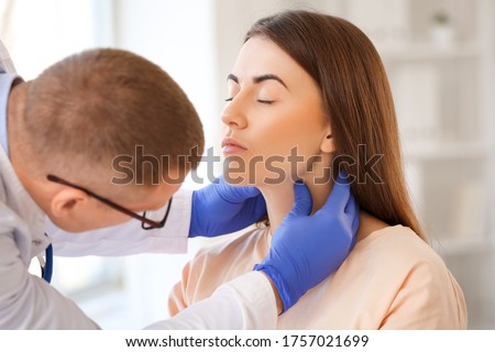 Endocrinologist examining throat of young woman in clinic Royalty-Free Stock Photo #1757021699