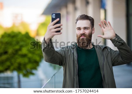 Hi there. Man smiling taking selfie photo smartphone urban background. Streaming online video call. Mobile internet. Hipster mobile phone.