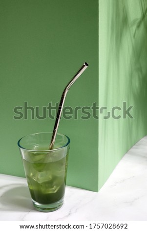 Green fresh cold drink with ice on green background