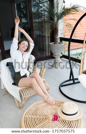 Young woman relaxing at the beautiful terrace in the swing chair