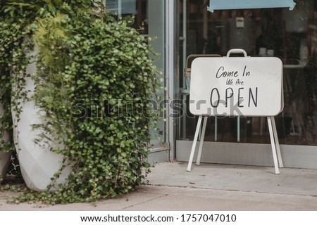 Reopening of a small business activity after the covid-19 emergency, ended the lockdown and quarantine. A business sign that says now we are open support local businesses hang on door at entrance.