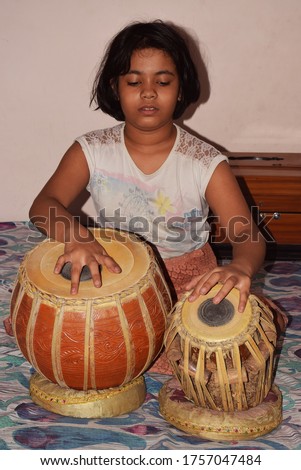 Indian Child playing Tabla which is a traditional Musical instrument